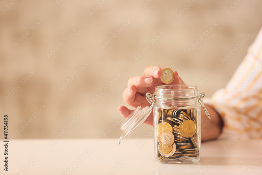 Senior woman putting coin in jar at table. Concept of pension - obrazy, fototapety, plakaty 