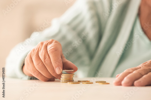 Senior woman counting coins on table. Concept of pension photo