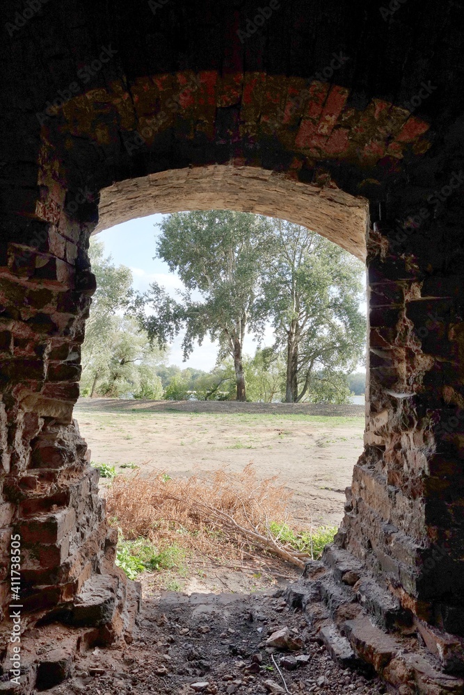 view of trees through an old window opening in the ruins of a granary in Modlin, Poland, Mazovia