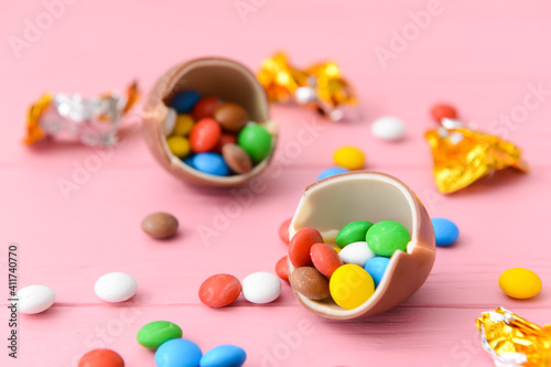Tasty chocolate egg and candies on color wooden background