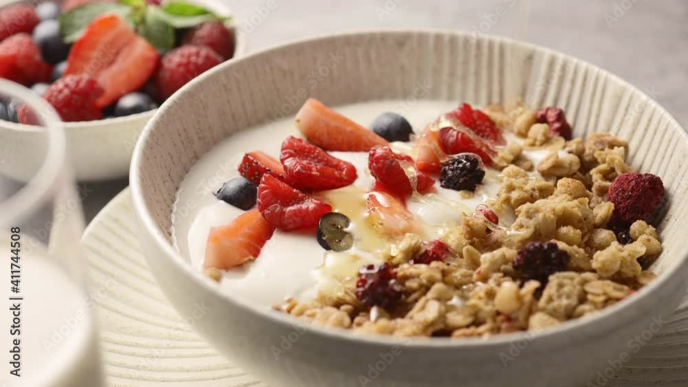 Granola with yogurt and berries poured with honey, close-up, breakfast 