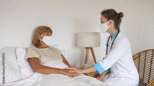 Private doctor visiting middle aged patient at home, treats and comforts her