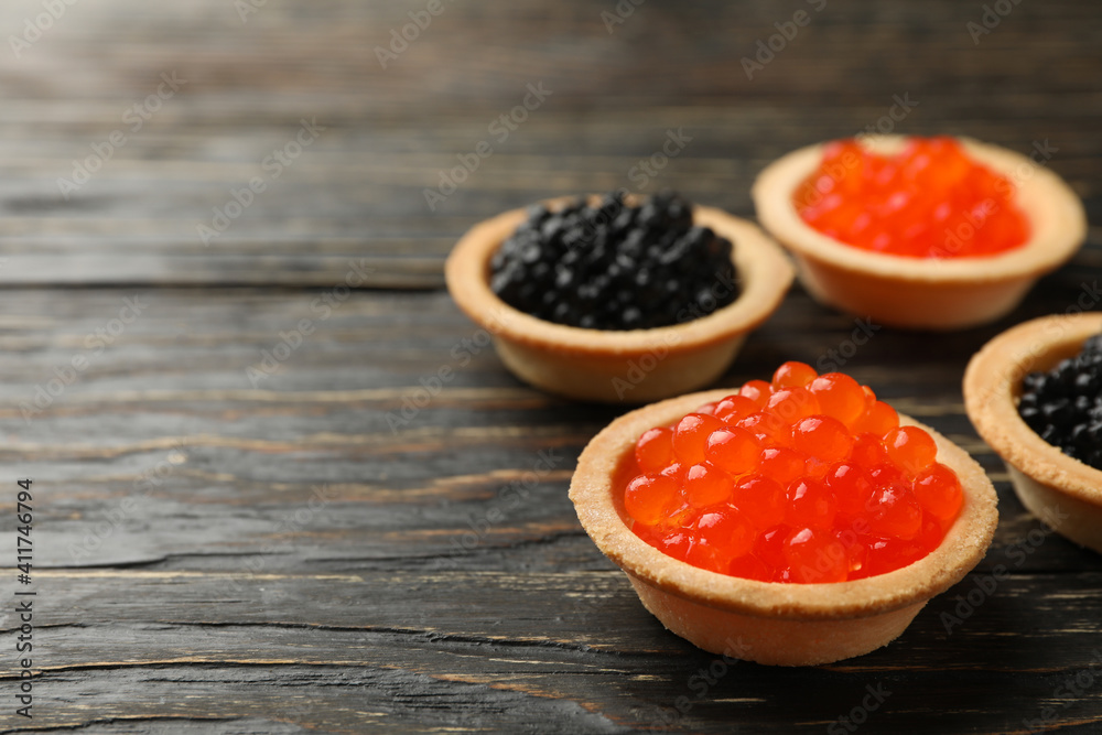 Tartlets with red and black caviar on wooden background, space for text Tartlets with red and black caviar on wooden background, space for text