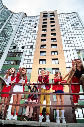 Group of fun children in stylish clothes near big modern house in the city