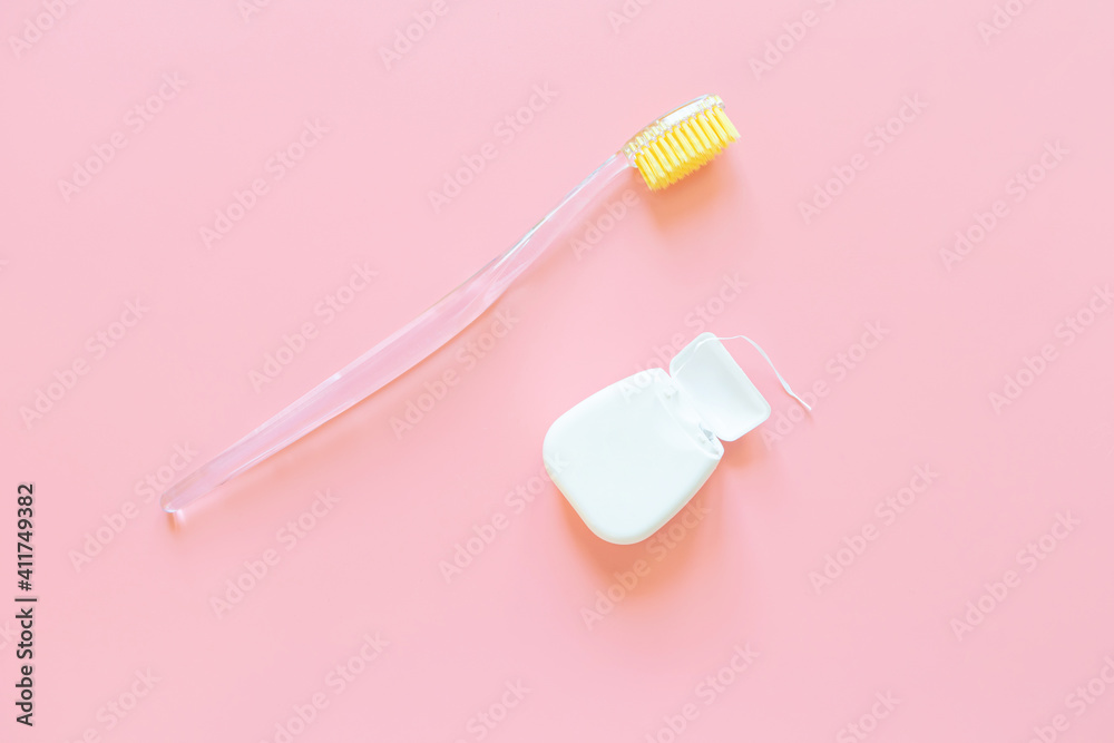 Toothbrush with yellow bristles and dental floss on a pink background. Oral hygiene, dentistry, teeth cleaning concept. Minimalism, top view, copy space. Toothbrush with yellow bristles and dental floss on a pink background. Oral hygiene, dentistry, teeth cleaning concept. Minimalism, top view, copy space.