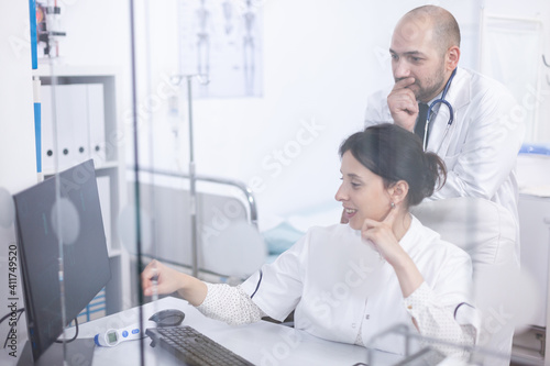 Young couple of doctors analysing medical scan on computer discovering the right treatment. Cardiologist showing and explaining results to his colleague using personal computer