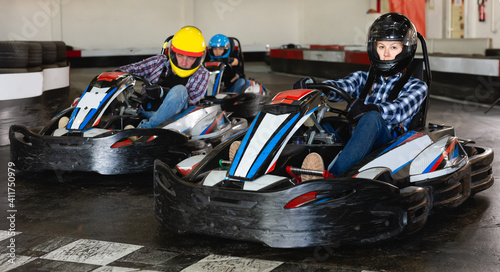 Jolly people in helmets driving cars for karting in sport club indoor