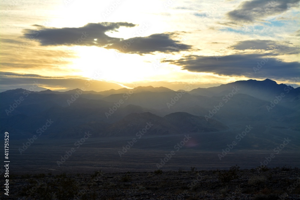evening sky with the sun breaking through clouds with a view to the panamint range and the Death Valley Wash in the National Park