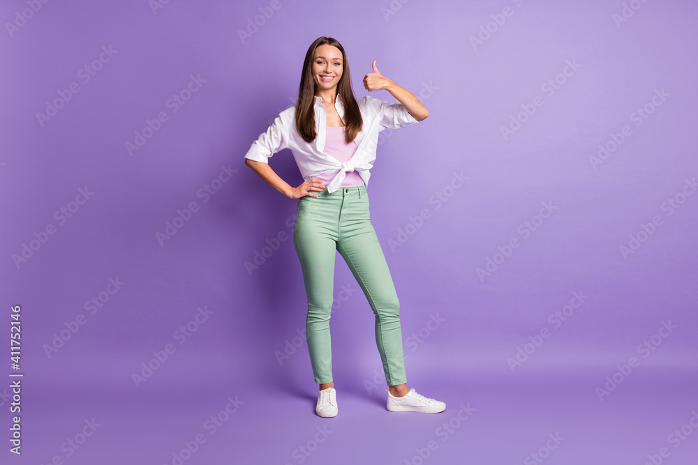 Photo of young adviser woman raise thumb up toothy beaming smile wear white shirt isolated violet color background Photo of young adviser woman raise thumb up toothy beaming smile wear white shirt isolated violet color background