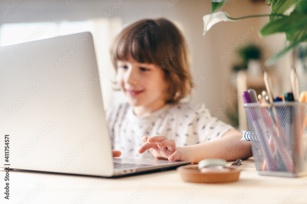 Distance learning online education. Caucasian smile kid boy studying at home with laptop and doing school homework. Thinking child siting at table with notebook. Back to school. Distance learning online education. Caucasian smile kid boy studying at home with laptop and doing school homework. Thinking child siting at table with notebook. Back to school.