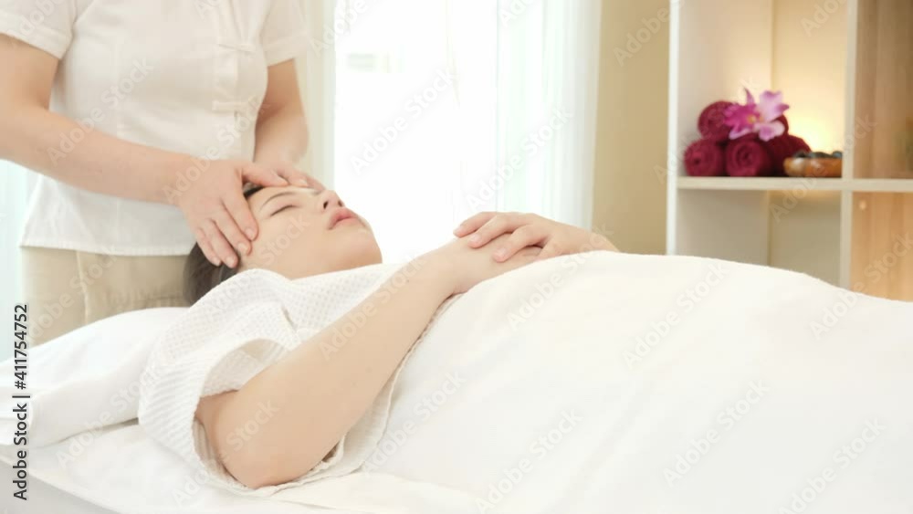 Young Asian woman getting spa massage treatment at beauty spa salon. Face massage, Relaxing massage, Spa skin and body care. slider shot Young Asian woman getting spa massage treatment at beauty spa salon. Face massage, Relaxing massage, Spa skin and body care. slider shot