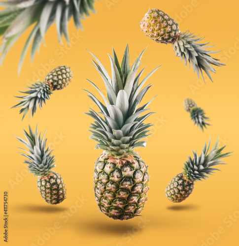 Fresh ripe pineapple with leaves falling in the air on the yellow background. fresh fruit levitation concept.