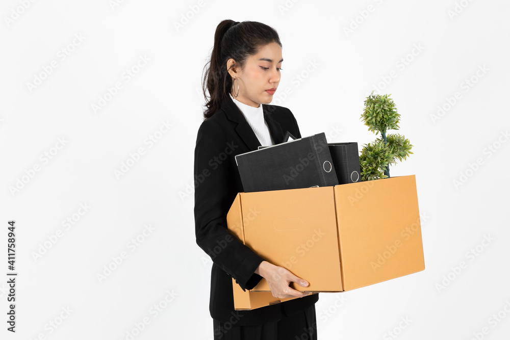 Fired dismissal young Asian business woman in suit holding box with personal belongings on white isolated background. Unemployment, failure and layoff concept. Fired dismissal young Asian business woman in suit holding box with personal belongings on white isolated background. Unemployment, failure and layoff concept.