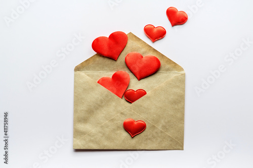 Valentine's day background- decorative red hearts and kraft envelope. Love romantic concept. Flat lay, top view, copy space.