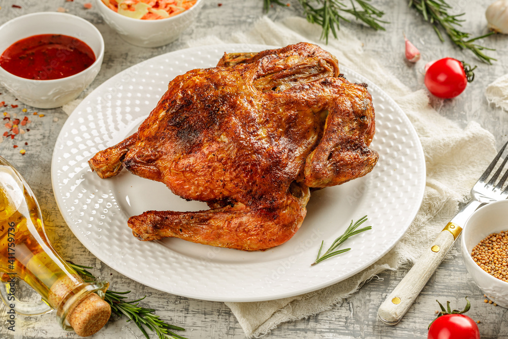 Tasty grilled fried roast chicken Tabaka in a white plate on concrete table with wegetables and spices Tasty grilled fried roast chicken Tabaka in a white plate on concrete table with wegetables and spices