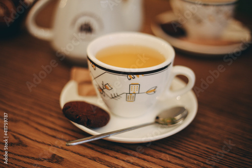 White cup of tea with brown cookies and spoon in cafe