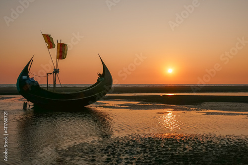 Scenic sunset seascape with beautiful traditional wooden fishing boat known as moon boat on beach, Cox's Bazar, Bangladesh