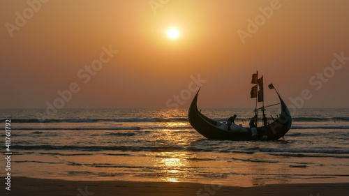 Traditional wooden fishing boat known as moon boat on beach near Cox's Bazar in southern Bangladesh at sunset getting ready to go