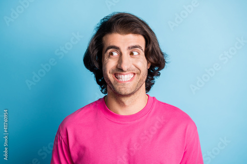 Photo of toothy smiling eastern man look empty space wear pink t-shirt isolated over blue color background © deagreez