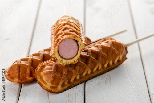 Appetizing waffle corn dogs on white wooden background photo