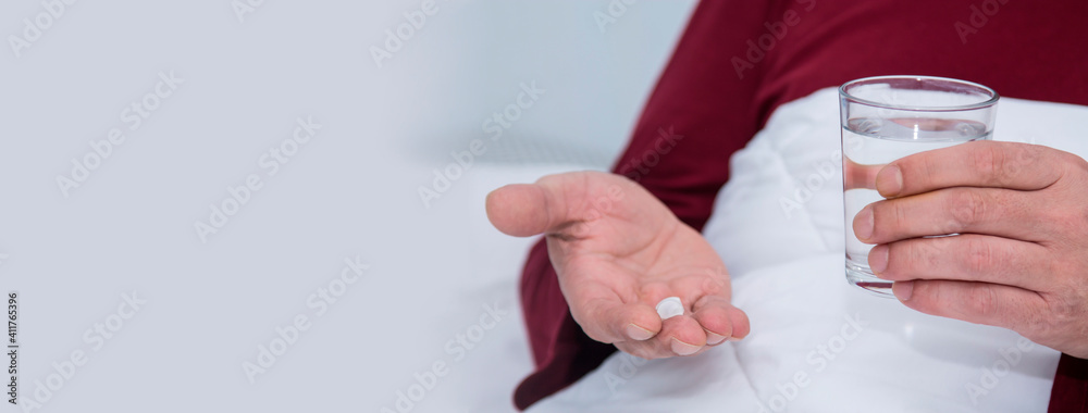 man in bed with pill and glass of water, healthcare and medicine concept