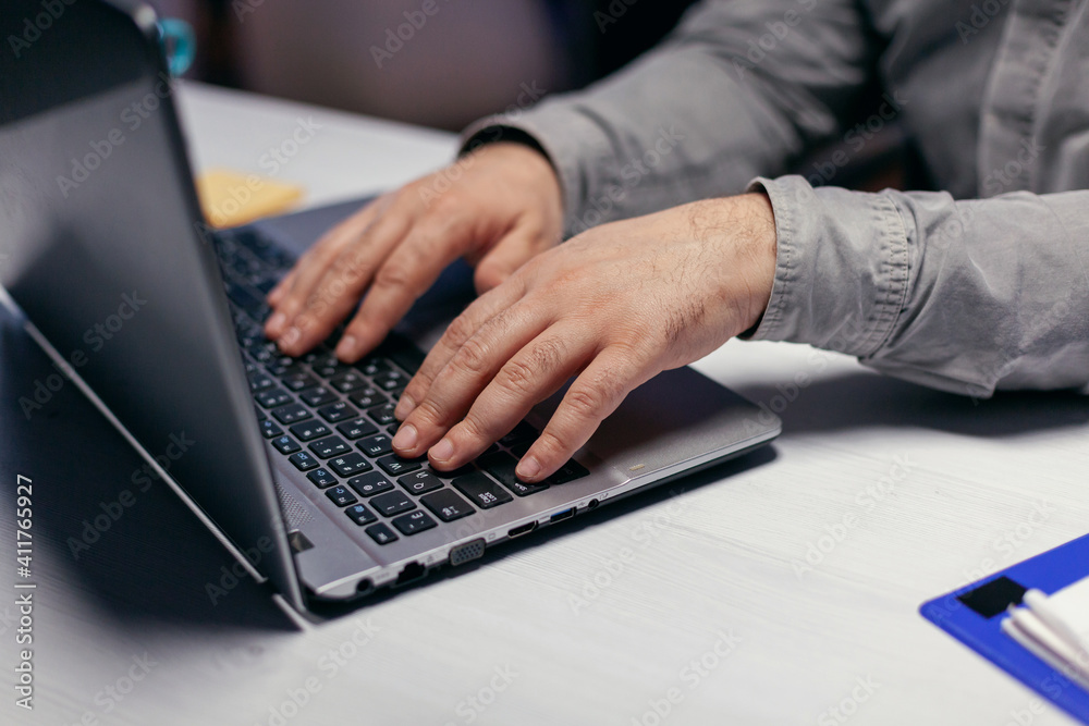 Close up of entrepreneur using laptop computer to finish project. . Male hands typing on laptop keyboard in office. Business, working from home, studying online concept