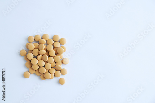 Brown round food supplement pills on white background.