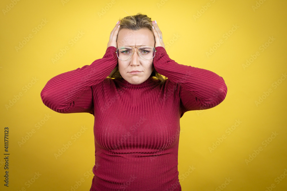 Young caucasian woman wearing casual red t-shirt over yellow background thinking looking tired and bored with hands on head
