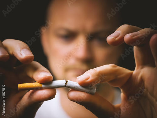 Принти на полотні Man breaking a cigarette into two to quit smoking