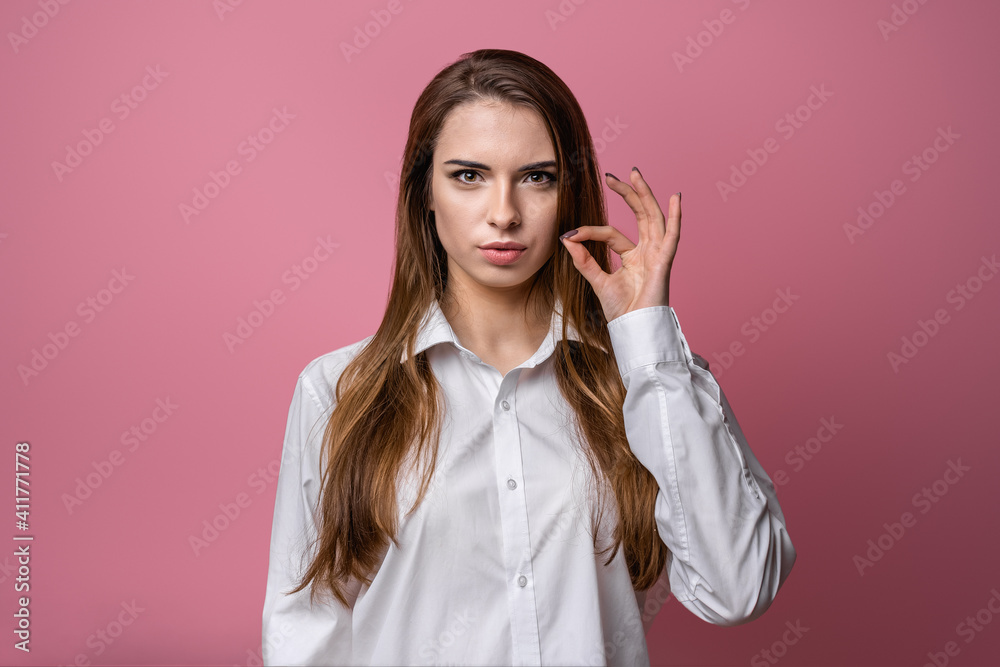 Brunette girl showing zip gesture as if shutting mouth on key. Studio shot, pink background. Keep a secret Brunette girl showing zip gesture as if shutting mouth on key. Studio shot, pink background. Keep a secret