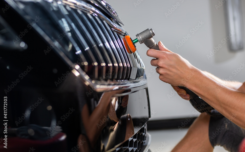 Obraz premium Close up of car detailist hands, cleaning or pilishing the car by poliermaschine, car detailing concept