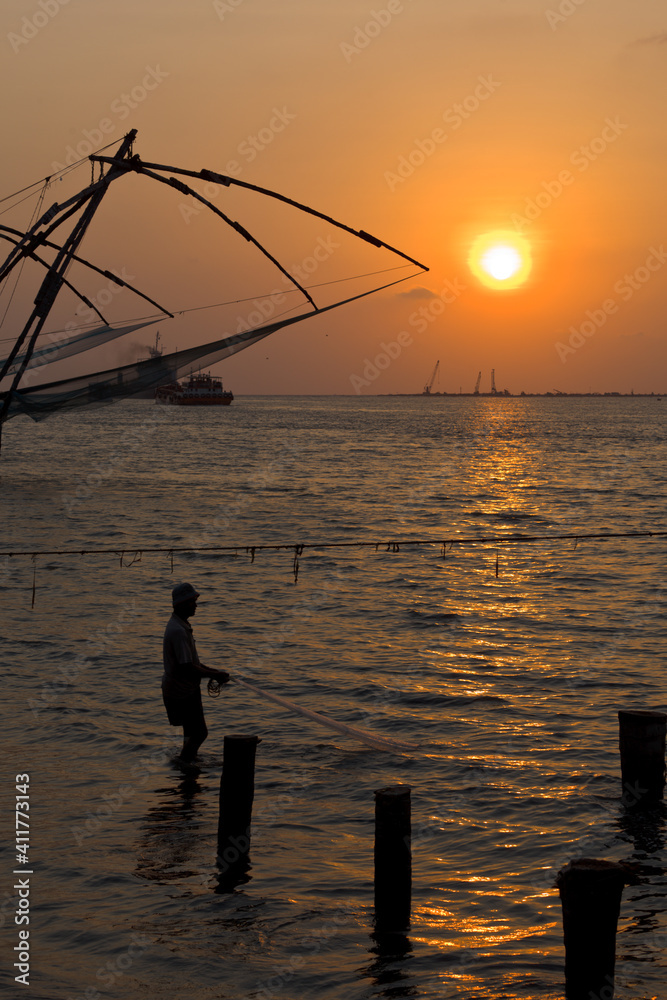 Fisherman and chinese fishnets on sunset. Kochi, Kerala, India