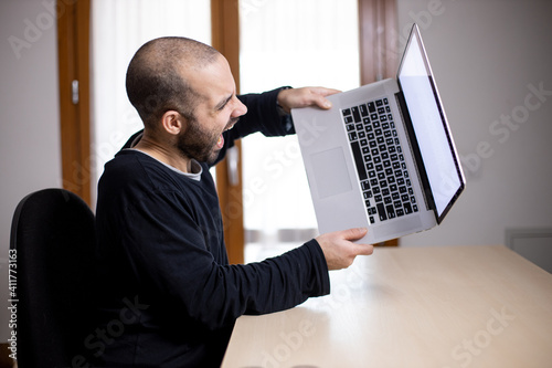 Fotografie Caucasian man is going crazy and throw away his laptop