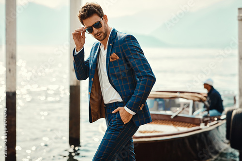 Photo Young handsome man in classic suit wear sunglasses over the blurred lake