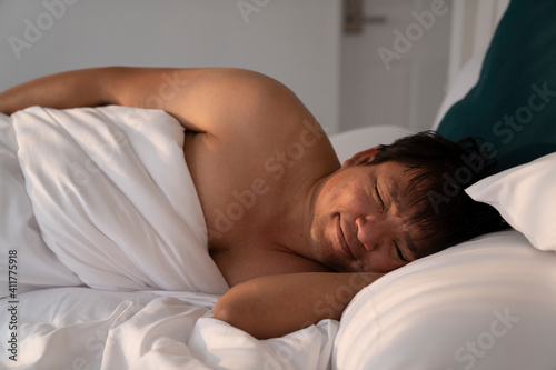chubby asian man sleep with smiling face in white bed, sweetdream, relax