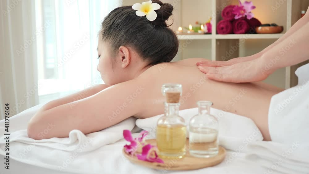 Rear view Young Asian woman getting Relaxing oil massage at beauty spa salon. Body massage, Massage for health. slider shot slow motion Rear view Young Asian woman getting Relaxing oil massage at beauty spa salon. Body massage, Massage for health. slider shot slow motion