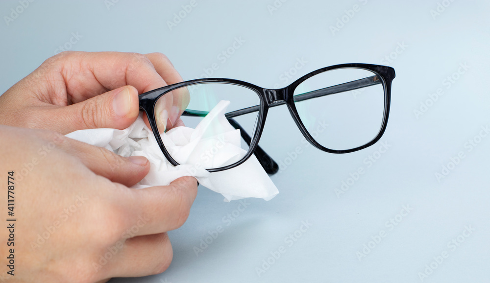 Person Cleaning Black Eyeglasses With Special Wipes Person Cleaning Black Eyeglasses With Special Wipes
