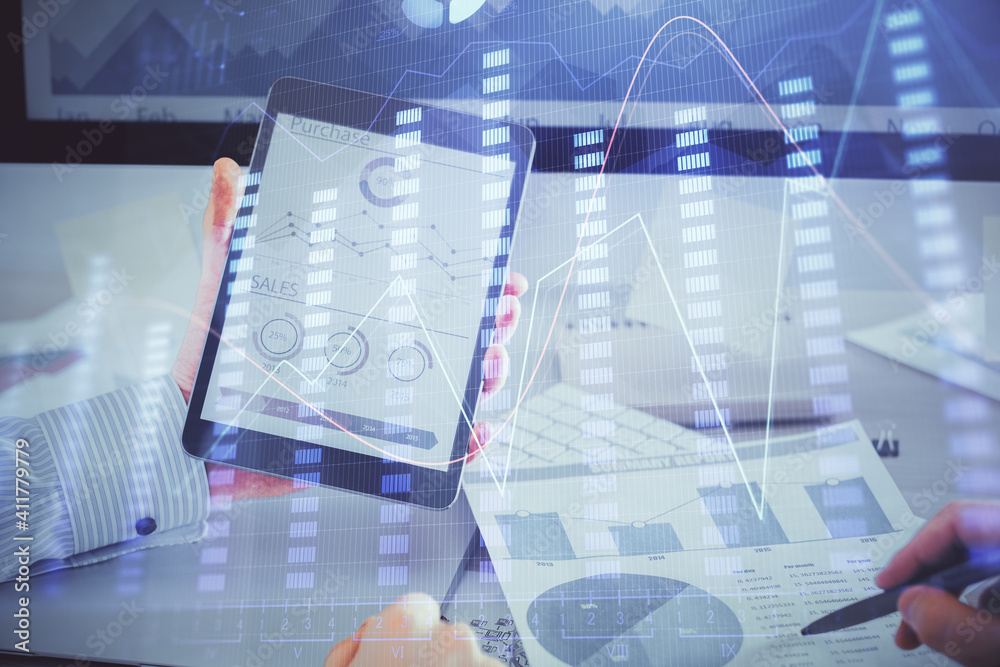 Double exposure of man's hands holding and using a digital device and forex graph drawing. Financial market concept.