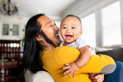 Obraz na płótnie Asian American father hugging his little son