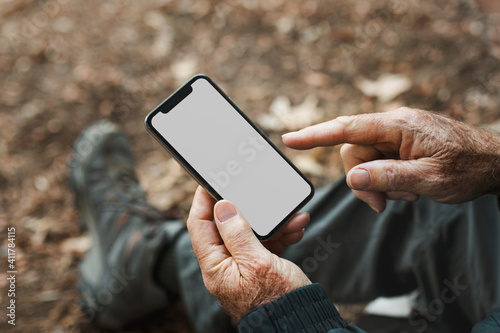 Senior man holding smartphone with white screen