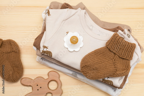 clothes, pacifier and toys for the newborn on a wooden chest of drawers