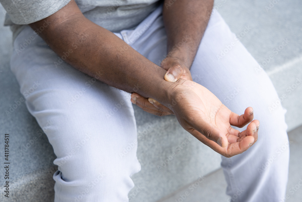 African man suffering from wrist or hand pain, sick black man with CTS, wrist pain, trigger finger, bone arthritis, gout symptoms, De quervain's disease, joint sickness, health care or pain concept African man suffering from wrist or hand pain, sick black man with CTS, wrist pain, trigger finger, bone arthritis, gout symptoms, De quervain's disease, joint sickness, health care or pain concept
