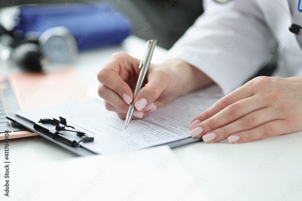 Doctor filling out patients medical history in office closeup Doctor filling out patients medical history in office closeup