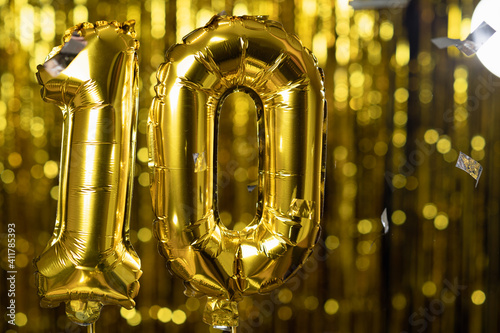 Gold foil number 10 ten festive balloon on a yellow background. The concept of birthday, anniversary, date.