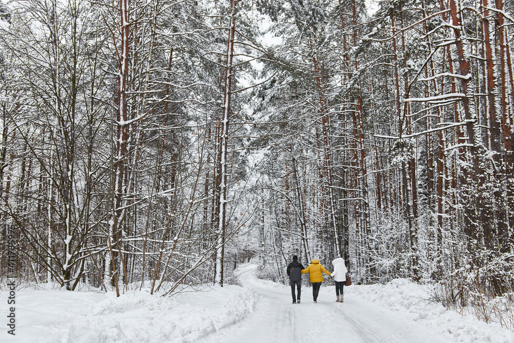 A family walks through the forest in the snow in winter