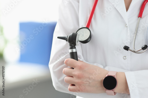 Otorhinolaryngologist holding otoscope in his hands in clinic closeup
