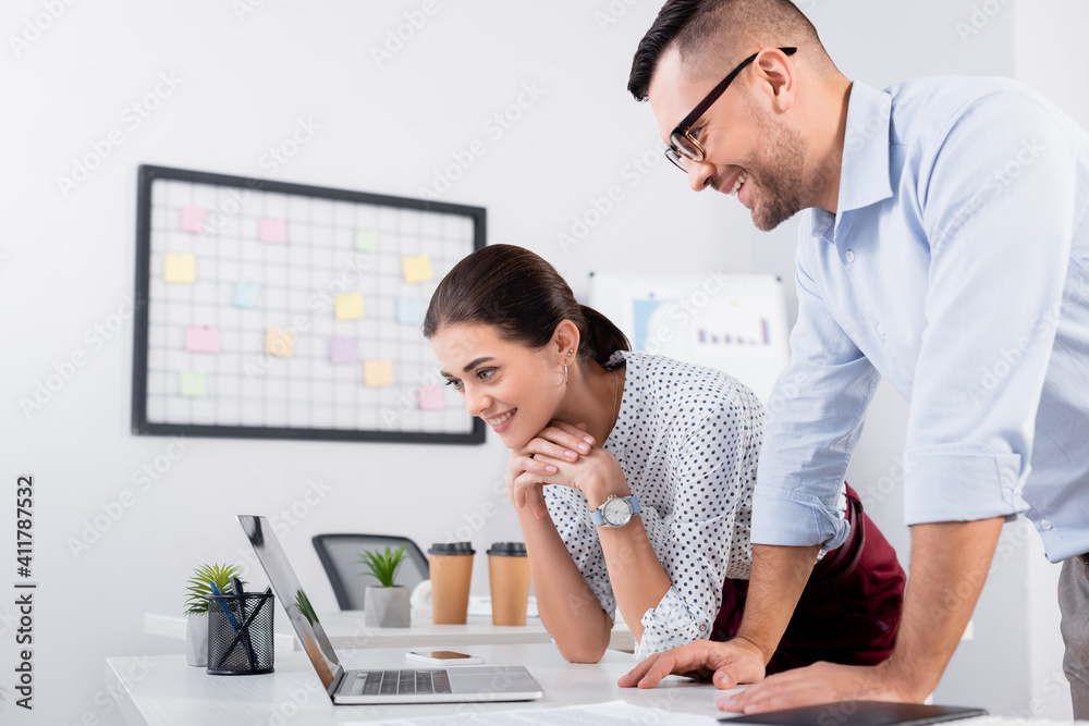 happy business people looking at laptop on desk