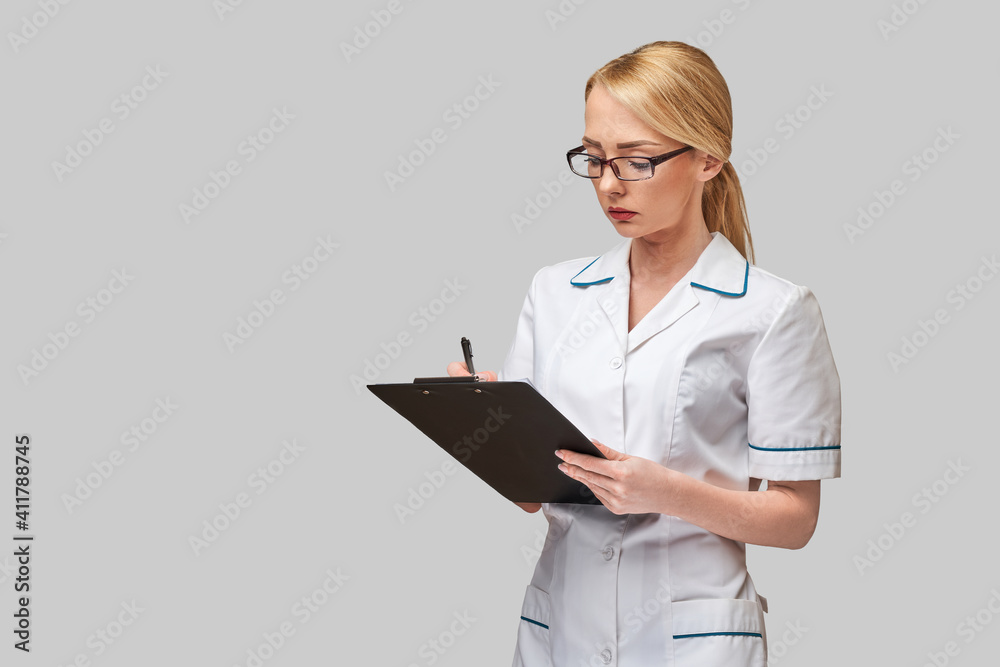 beautiful female doctor holding clipboard isolated on grey background beautiful female doctor holding clipboard isolated on grey background