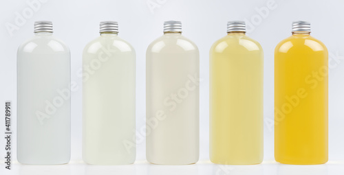 Assortment of plastic tall bottles with  cosmetic produce or perfume of different pastel pale colors, silver cap mockup on white background, template. photo