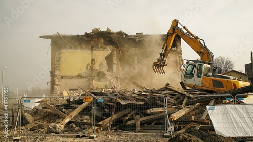 Yellow excavator destroys building. Heavy duty machine is demolishing a brick building. Demolition of the building . Demolition construction work aerial drone photo